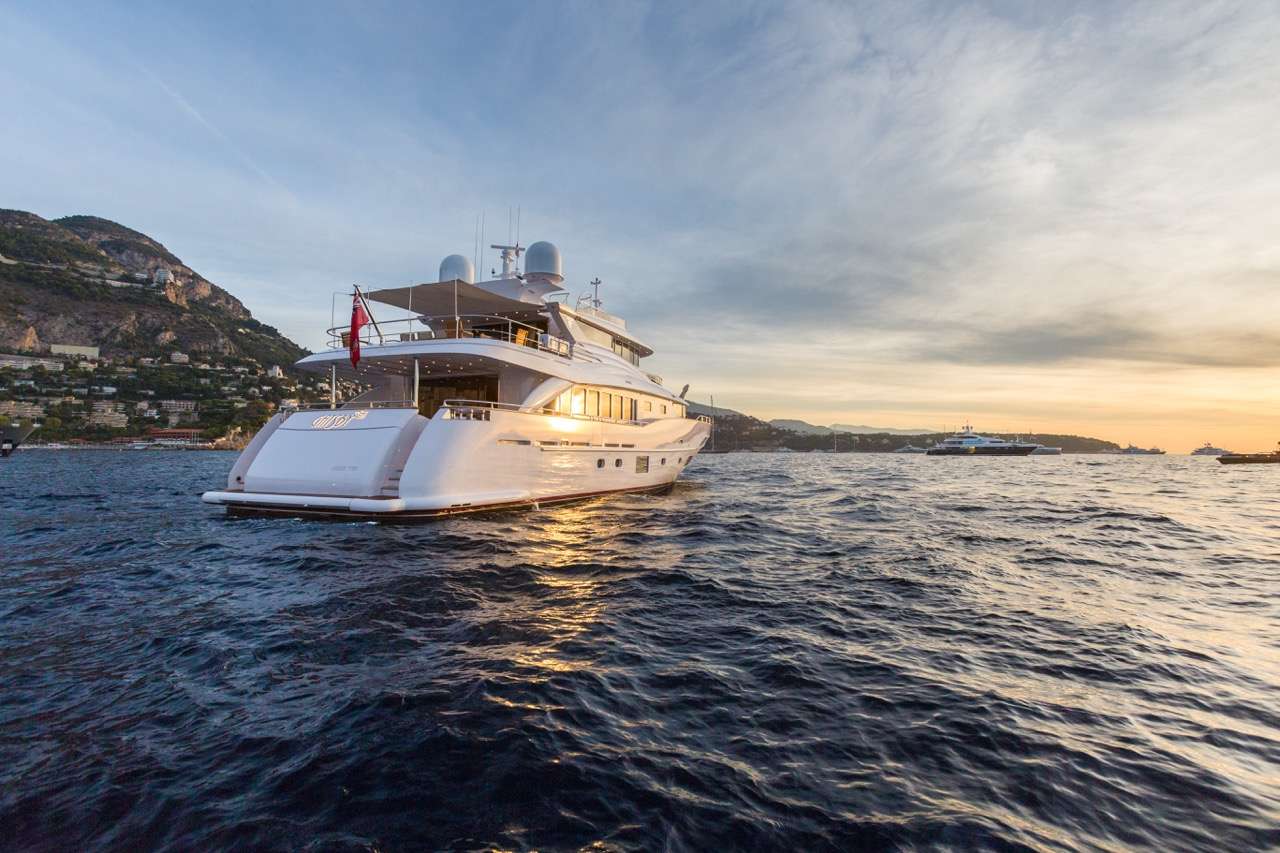 Motor yacht underway off a Mediterranean coast at sunset