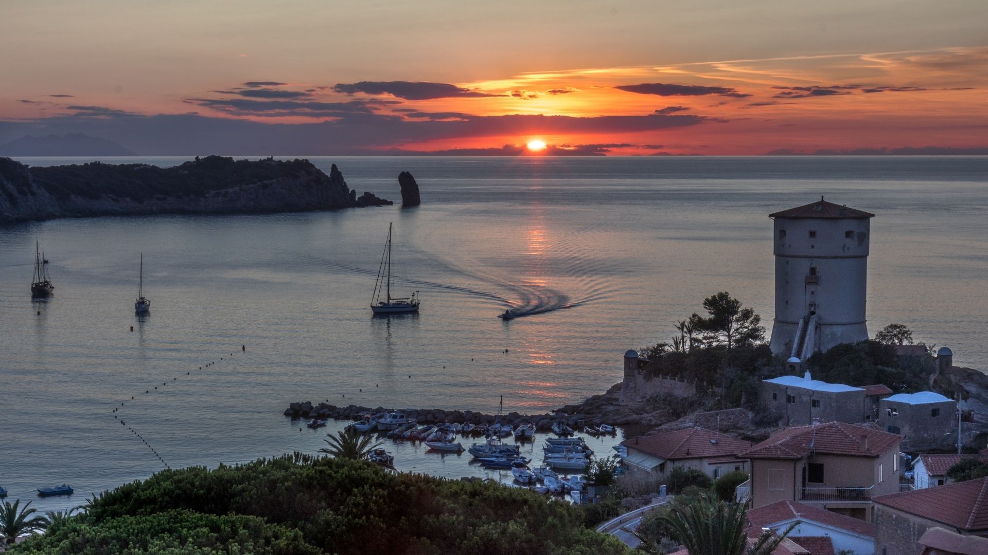Giglio Porto and the climb up to Giglio Castello — the medieval hilltop village fortified in the eleventh century by the Aldobrandeschi family. The harbor is small; the village above walks in twenty minutes from end to end inside the Aldobrandeschi walls.