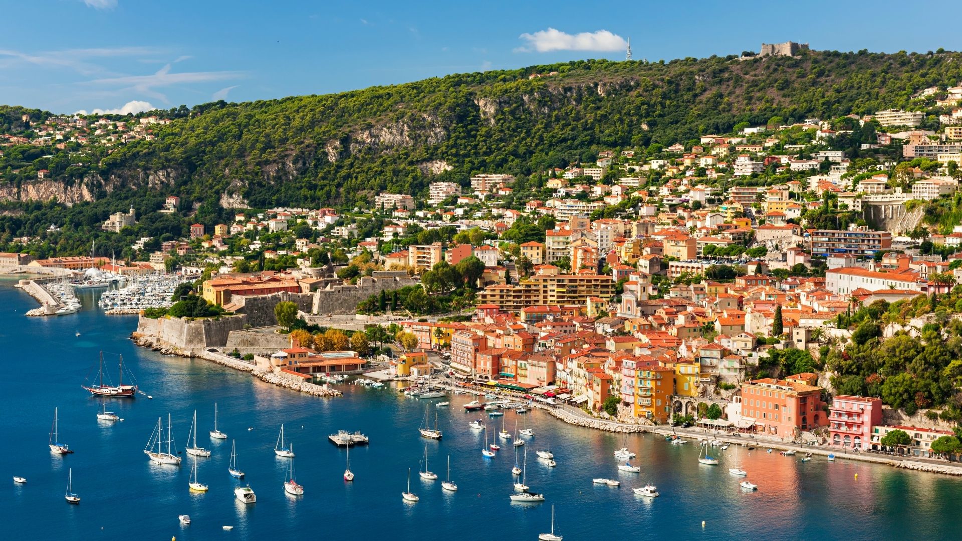Yacht at anchor on the French side — the cleaner overnight option versus Menton's small inner harbor if the group prefers a quieter mooring than the village quay. The deep water inside Menton's coast gives clean anchoring sheltered from the prevailing summer wind.