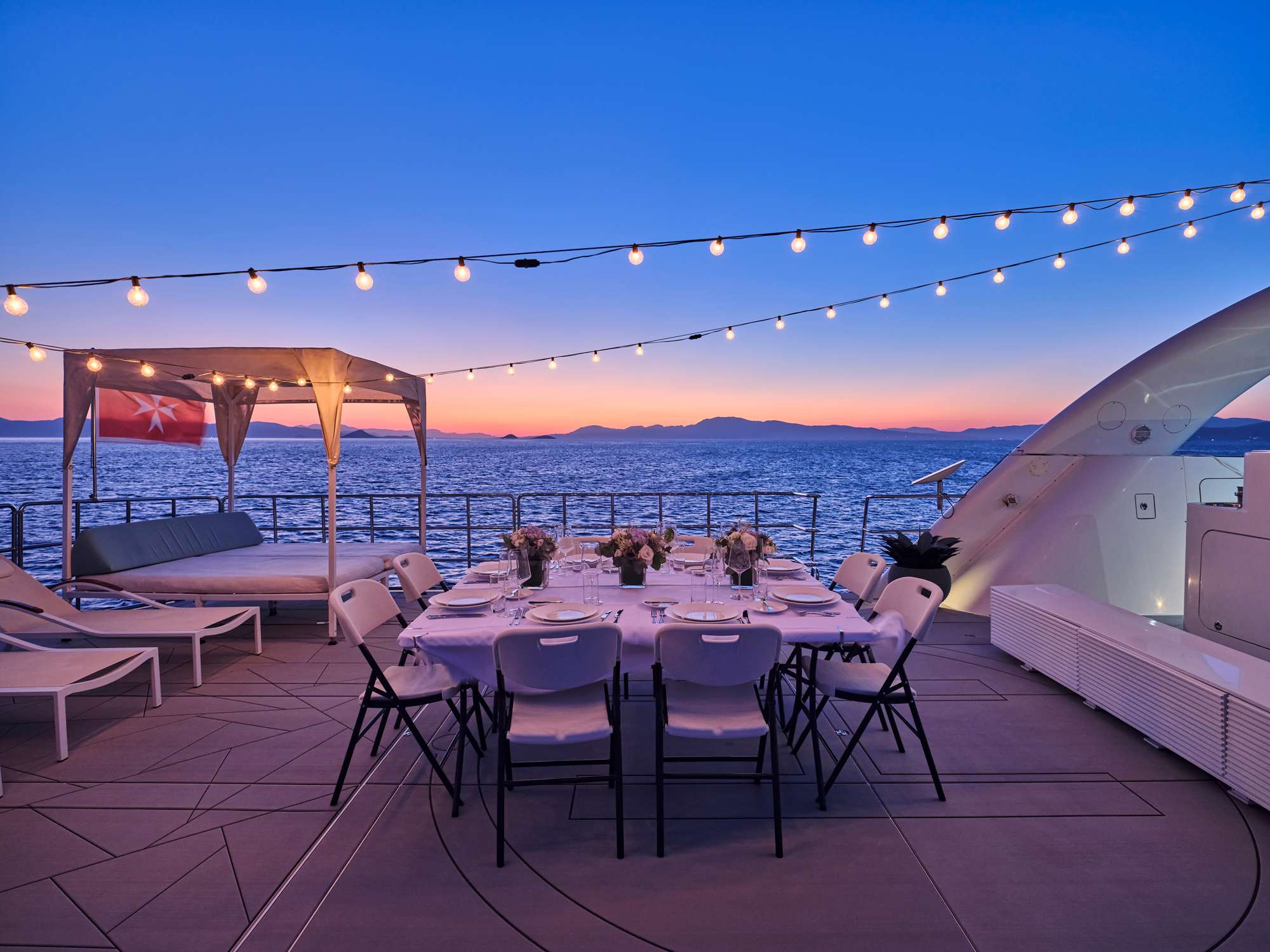 Aft-deck dinner set at sunset on a crewed yacht at anchor in the Mediterranean