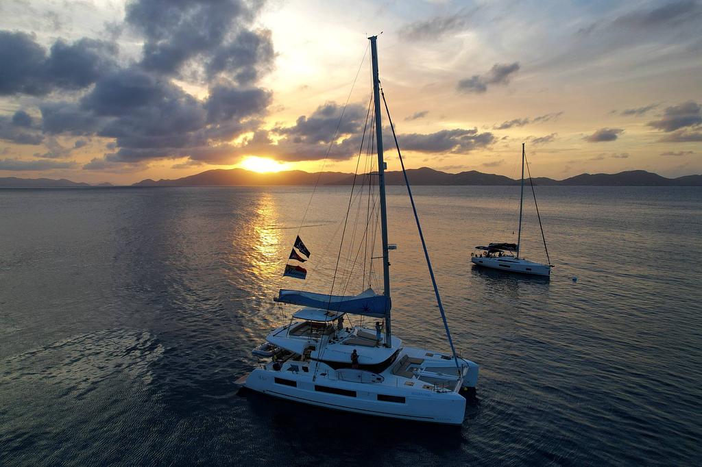 Our flags with a Cooper Island sunset over Tortola